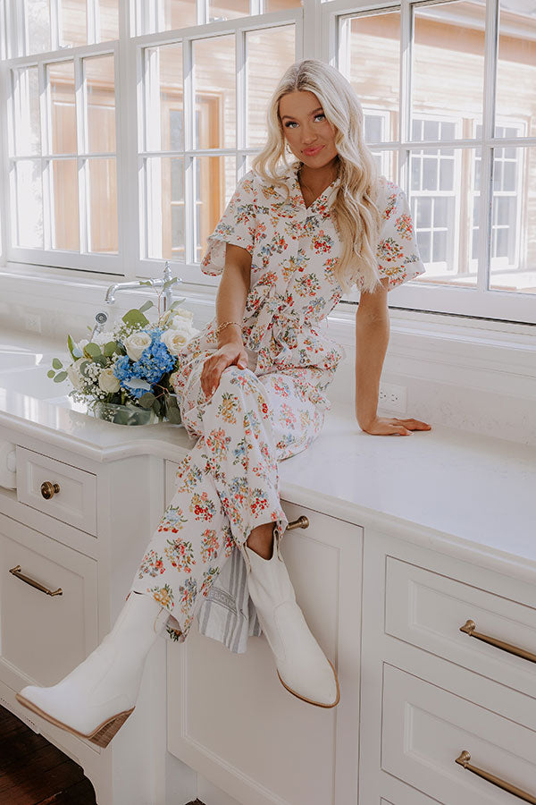 Cozy yet stylish white jumpsuit with delicate floral prints, paired with winter-ready white boots.